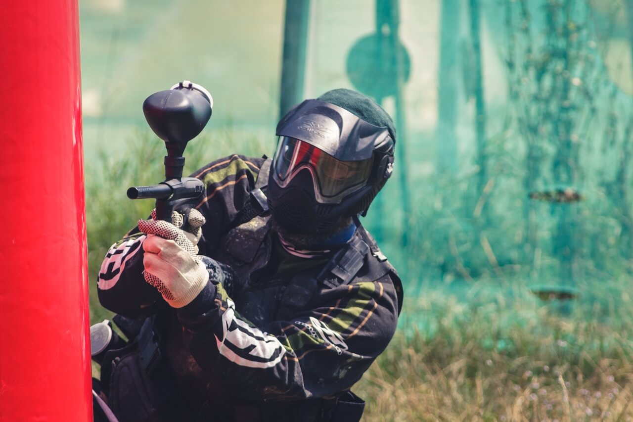 man holding paintball marker and playing paintball