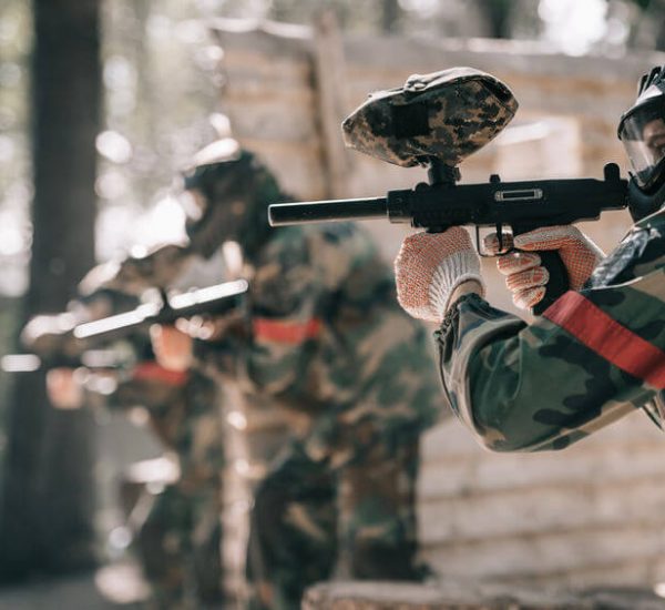 paintball player in goggle mask aiming with marker gun