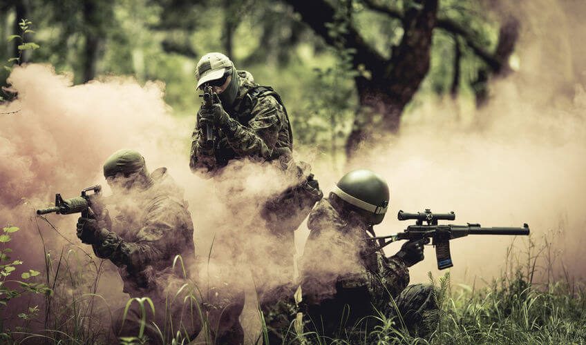 airsoft players holding guns amid smoke in forest