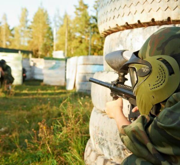 paintball player wearing mask and holding marker in knee position