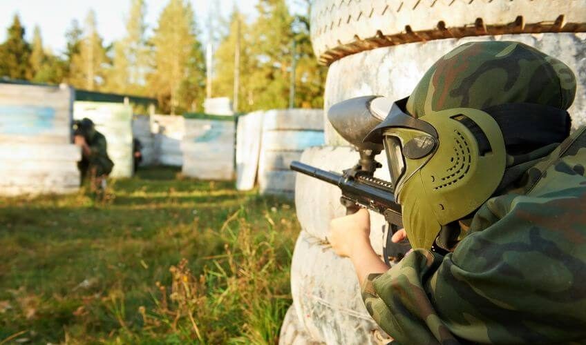 paintball player wearing mask and holding marker in knee position