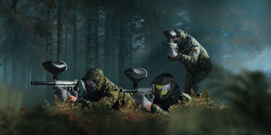 paintball team shooting with markers in forest battle