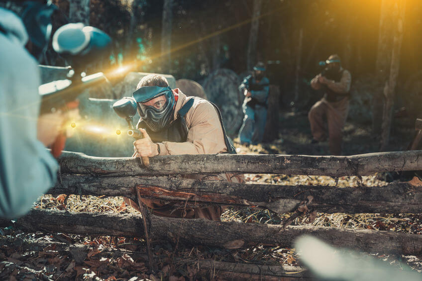 team of paintball players with marker guns and equipment