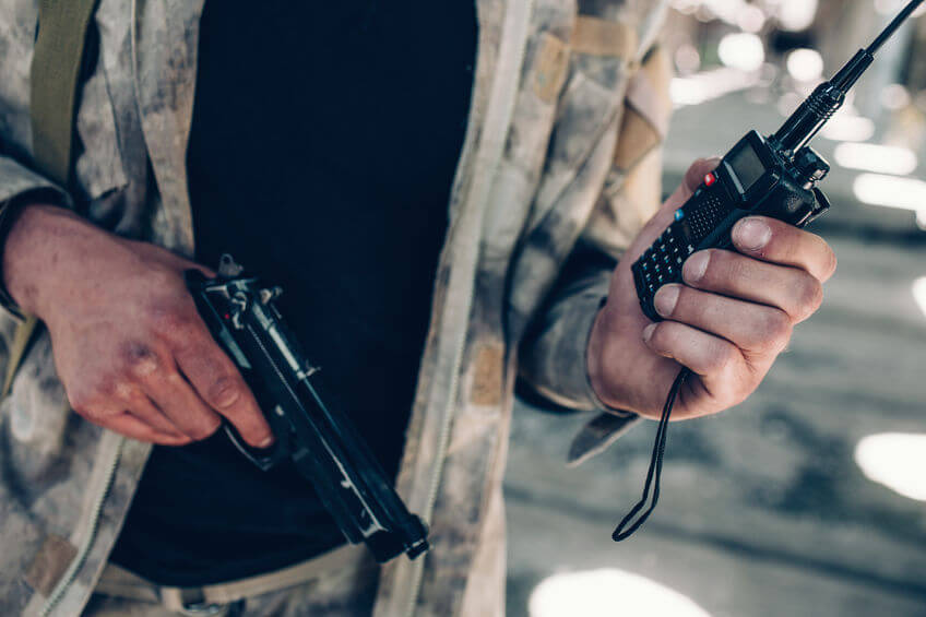 close up of soldiers hands holding portable radio airsoft pistol