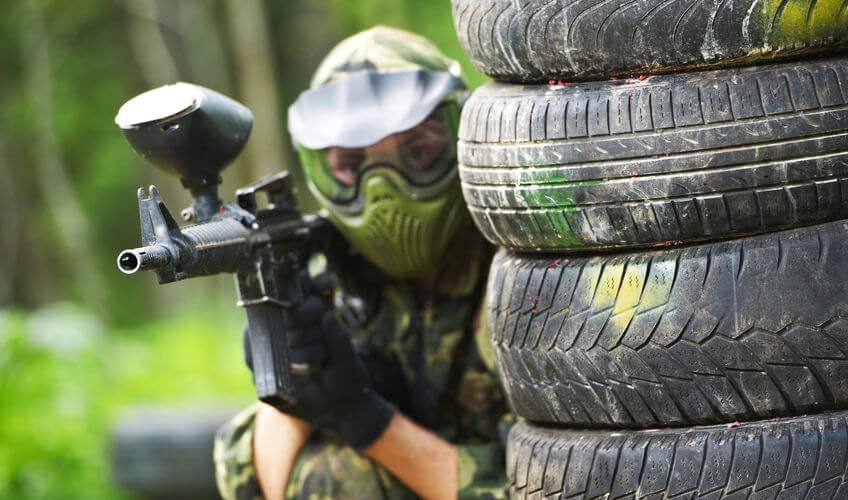 paintball player in protective uniform and mask aiming sniper rifle