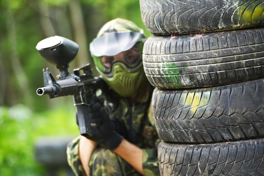 paintball player in protective uniform and mask aiming sniper rifle