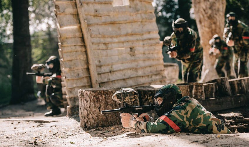 paintball players playing woodsball and aiming by markers