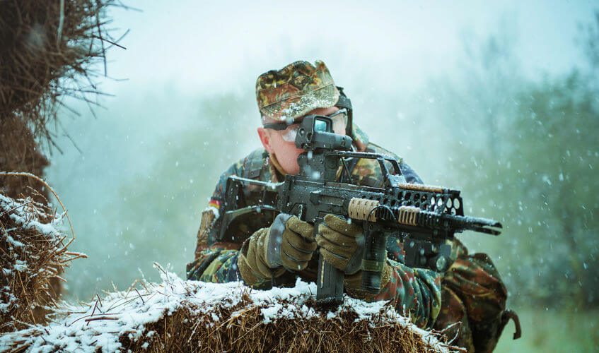 sniper with automatic airsoft rifle in winter