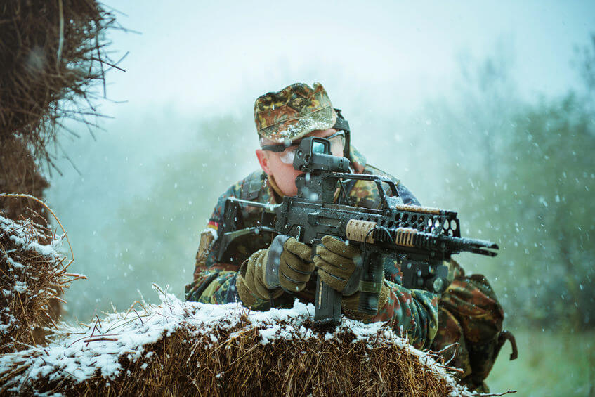 sniper with automatic airsoft rifle in winter