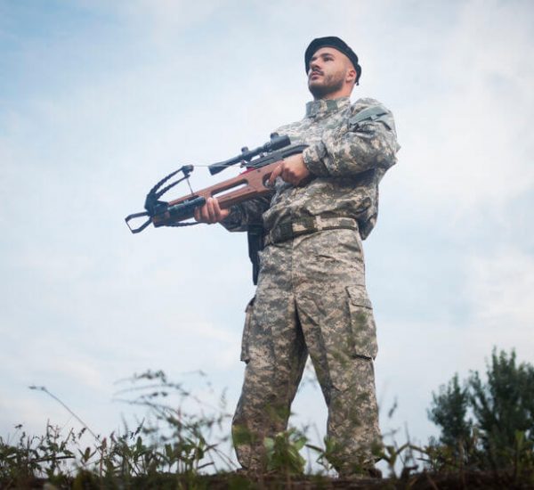 military guard is guarding with tactical crossbow weapon outdoors