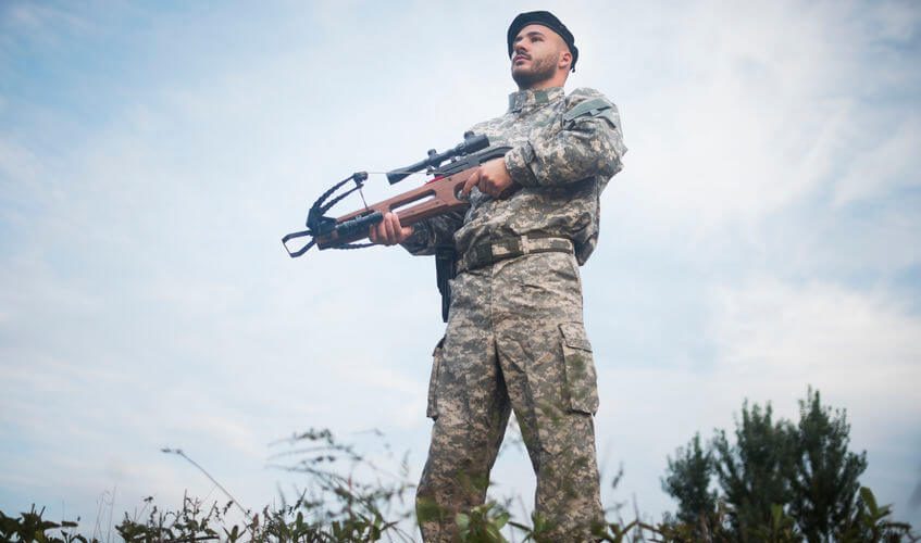 military guard is guarding with tactical crossbow weapon outdoors