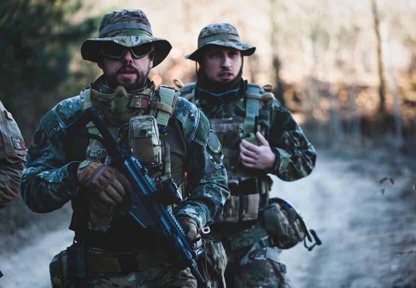 airsoft military game players with assault rifles