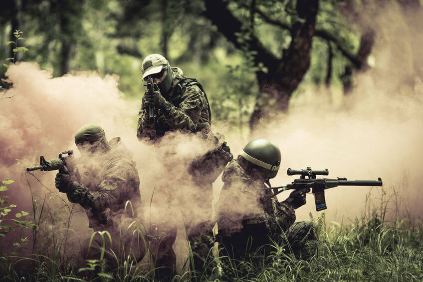 airsoft players holding guns amid smoke in forest