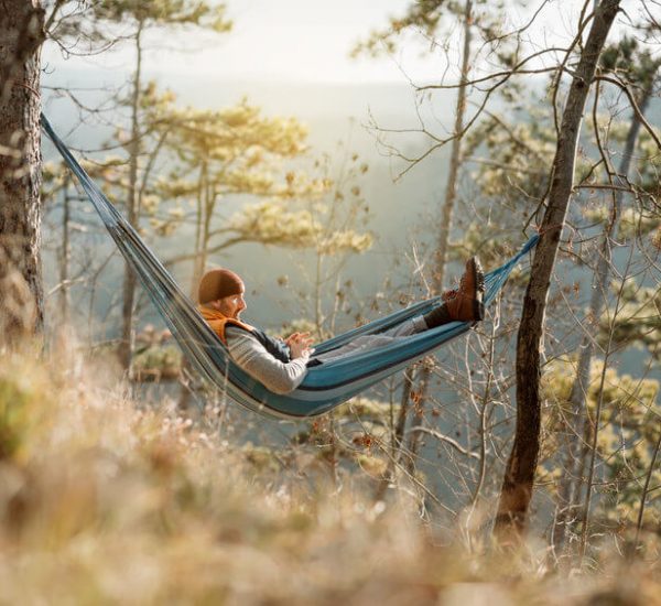 man relaxing in camping hammock
