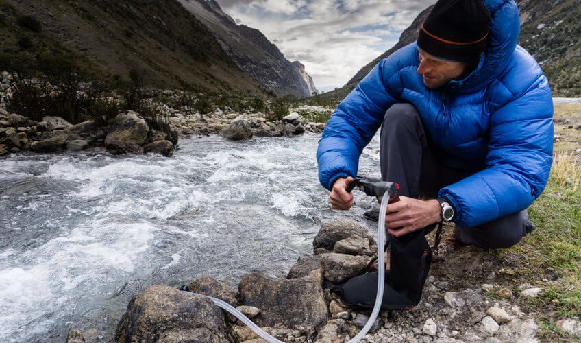 man using backpacking water filter
