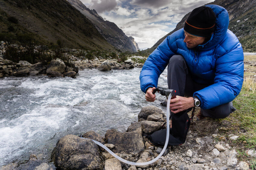 man using backpacking water filter
