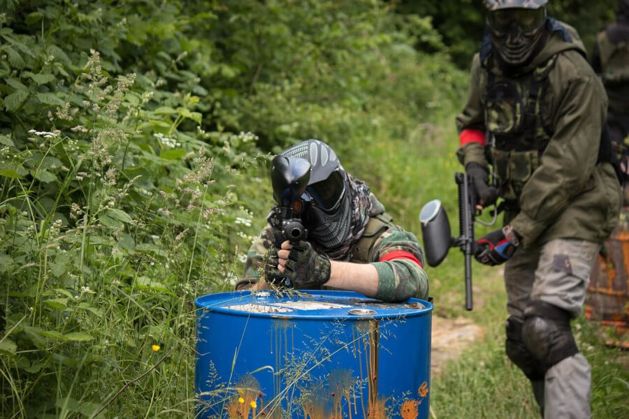 men playing paintball in wood