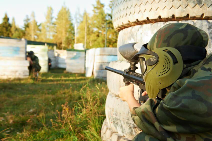paintball player wearing mask and holding marker in knee position