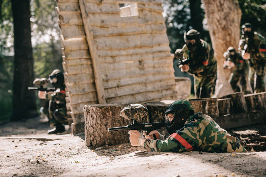 paintball players playing woodsball and aiming by markers