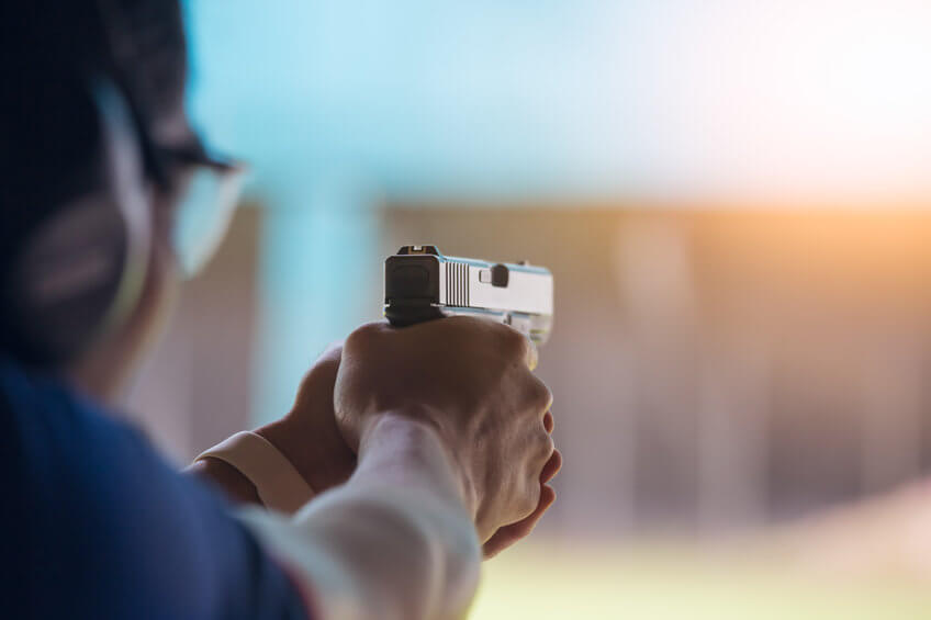 person aiming gun at shooting range