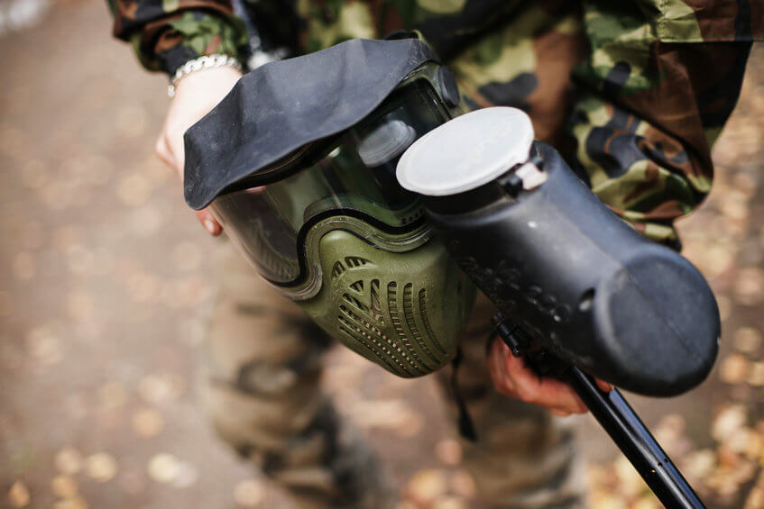 person holding paintball gun and mask